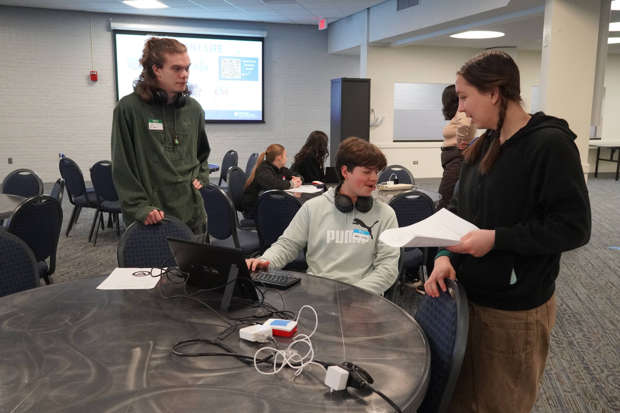 two gvsu students help high school student on laptop
